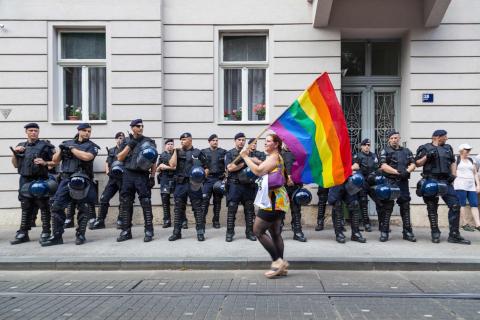 Editorial: 15th Zagreb pride. LGBTIQ activist passing by police cordon holding a rainbow flag, Croatia.