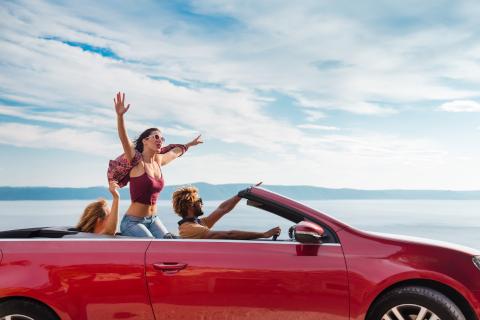 Lifestyle: Group of happy young group enjoying driving in red convertible sports car.